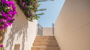 A staircase leading up to a door with a metal railing, surrounded by white walls and purple flowers. - Cava Li Santi Residence - Appartamento con Terrazza Int 4 (Santa Caterina)