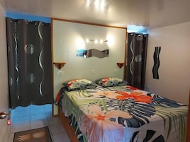 A bedroom with a bed, a mirror, and a wall-mounted light fixture.