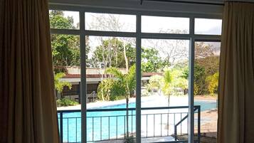 Una habitación con un amplio ventanal corredero que da a una zona con piscina.