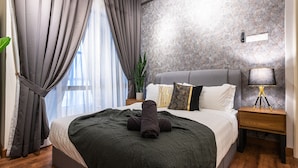 A modern hotel room with a large bed, grey curtains, a potted plant, a bedside lamp, and a wall-mounted control panel. - Instagrammable Arte Mont Kiara 2 Rooms (Kuala Lumpur)