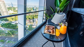 A balcony with a city view, a table with pastries, a drink, and a plant. - Instagrammable Arte Mont Kiara 2 Rooms (Kuala Lumpur)
