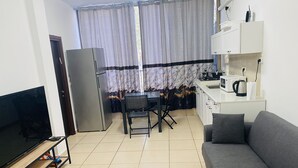 Un espacio habitable compacto con televisión, kitchenette, comedor y sofá.