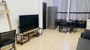 Una sala de estar con televisor, refrigerador, mesa de comedor con sillas y sofá.
