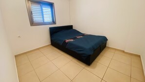 Una habitación pequeña con cama individual, ventana y aire acondicionado.