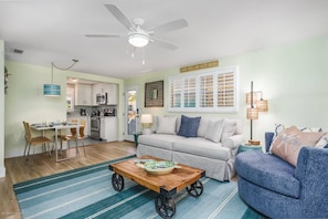 A living room with a sofa, a coffee table, and a dining area with chairs and a table.