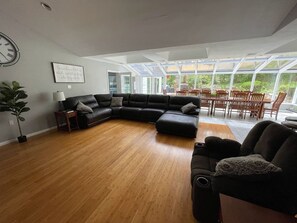 Ein geräumiges Wohnzimmer mit einer Eckcouch, einem kleinen Tisch und einer Zimmerpflanze.