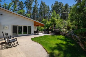 A modern house with a covered patio, a lawn, and a stone wall. - 201 S berry  · lNDOOR POOL! The FUN house (Rapid City)
