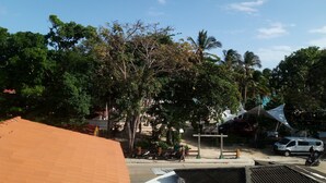 A street scene with trees, a white van, and a blue canopy. - San San Andrés Magic House 0 by BBBSAI (San Andrés y Providencia)