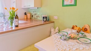 A kitchen with white cabinets, a wooden countertop, and a table set with plates, cups, and a teapot.