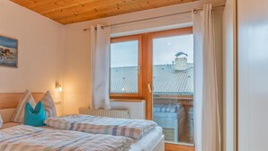 A bedroom with a bed, pillows, a window, and a view of buildings outside.