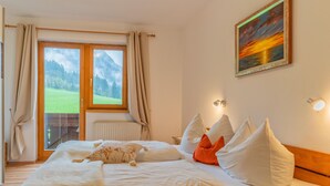 Habitación de hotel con una cama, vistas a un paisaje montañoso y un cuadro en la pared.
