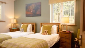 Een hotelkamer met twee bedden, een schilderij aan de muur en een raam met uitzicht op bomen.