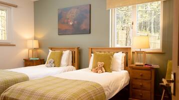 A hotel room with two beds, a painting on the wall, and a window with a view of trees.