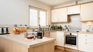 Een moderne keuken met een centraal eiland, een magnetron, een oven en een koffiezetapparaat.
