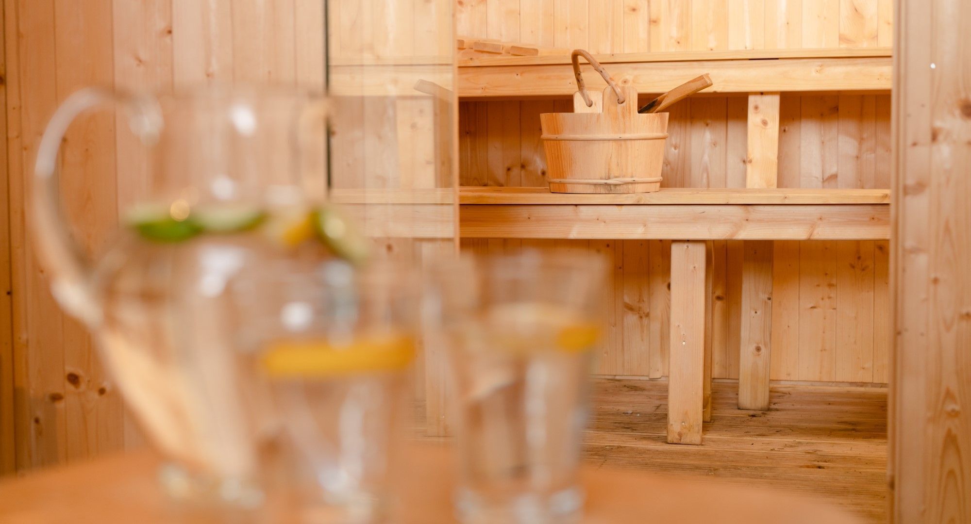 Un intérieur en bois, avec une table en bois et un pichet en verre transparent doté d’une anse.