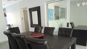 Ein Essbereich mit einem dunklen Holztisch, sechs schwarzen Stühlen und einer roten Tischdecke.