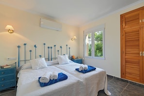 A double bed with white linens and blue towels, a nightstand with a lamp, and a wooden wardrobe.