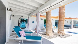 A modern outdoor lounge area with blue lounge chairs, a hanging chair, and a pool. - The Orchid House - Palm Springs (Palm Springs)