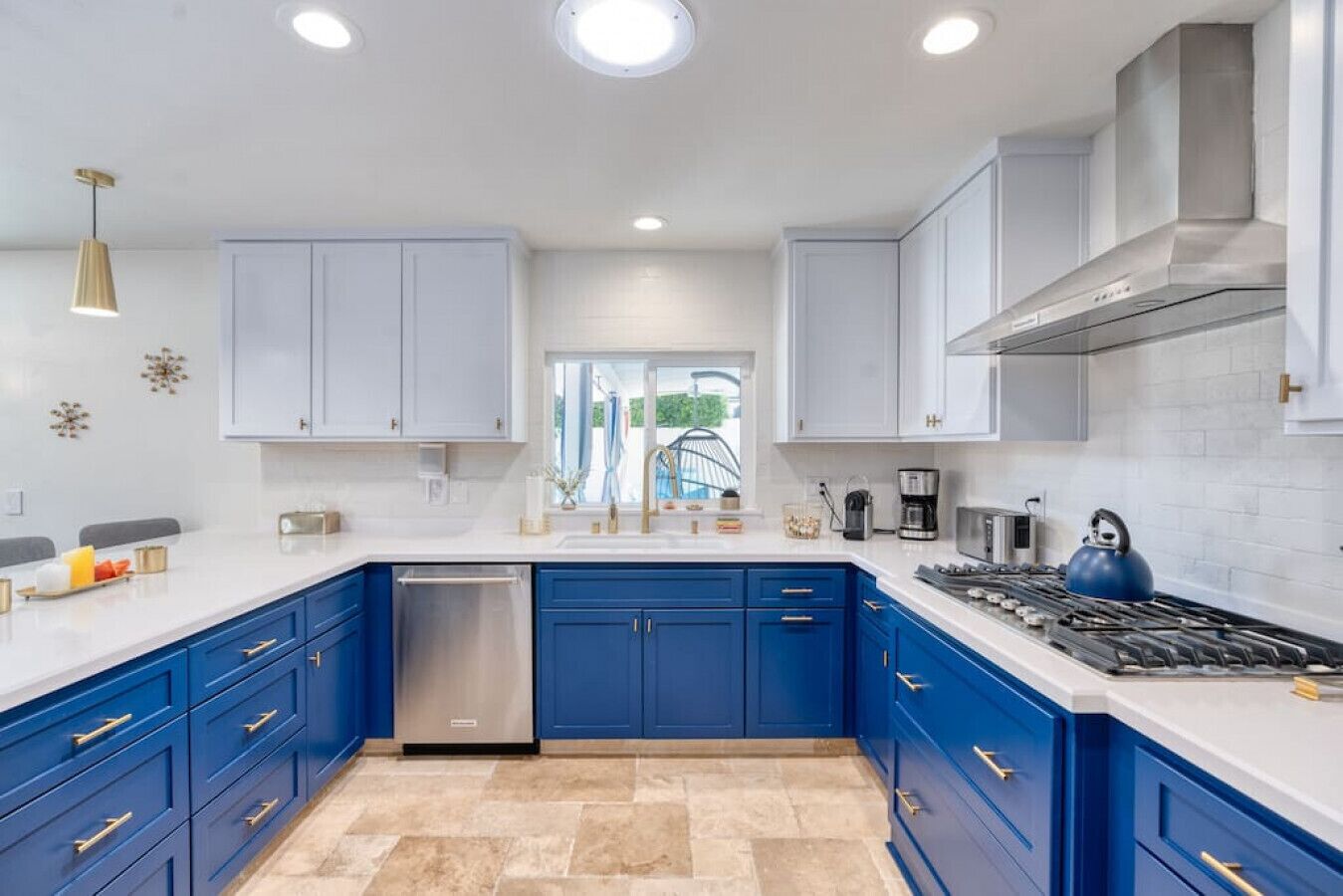 Una cocina moderna con armarios azules, encimeras blancas y un lavavajillas de acero inoxidable.