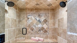A shower with a tiled wall, a shelf with towels, and two showerheads. - The Orchid House - Palm Springs (Palm Springs)
