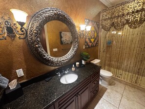 A bathroom with a large ornate mirror, a granite countertop, a sink, a toilet, and a shower area with a decorative curtain. - Luxury Villa, Pool, Spa, Dock, Waterfront, Theater (Merritt Island)