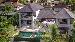 A large house with a swimming pool, surrounded by lush greenery and other houses. - Villa Lumi with Private Pool - 3BR (Pecatu)