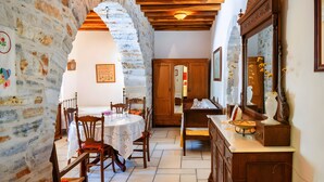 A dining area with a stone wall, wooden ceiling, and a table with chairs. - Zeus House Country Home with Mountain View, 2 Private Terraces & Wi-Fi (Naxos)