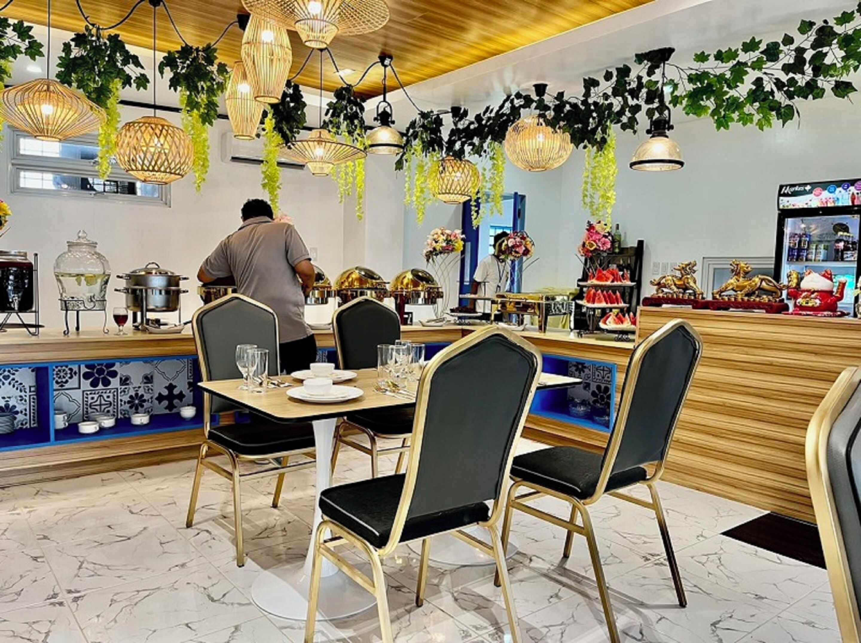 Un restaurant doté d’un bar, de tables avec des chaises et de plantes suspendues.