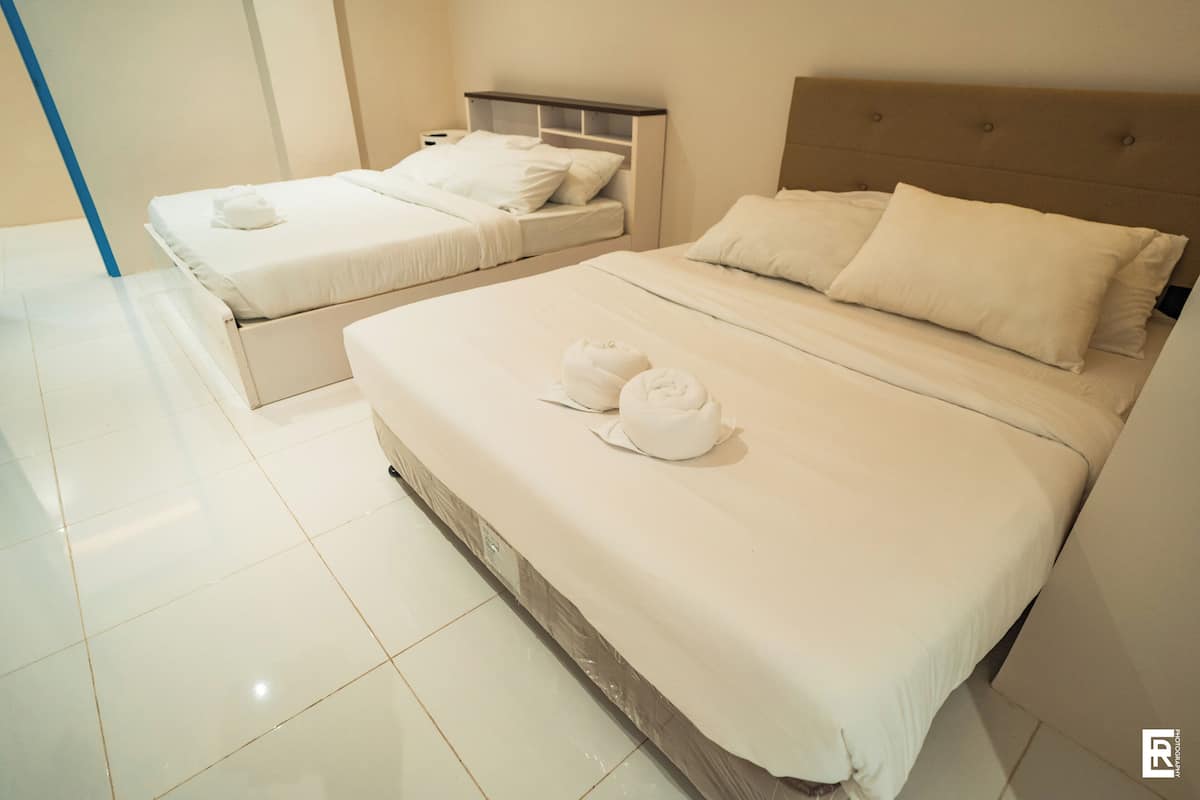 Una habitación de hotel con dos camas, cada una con ropa de cama y almohadas blancas.