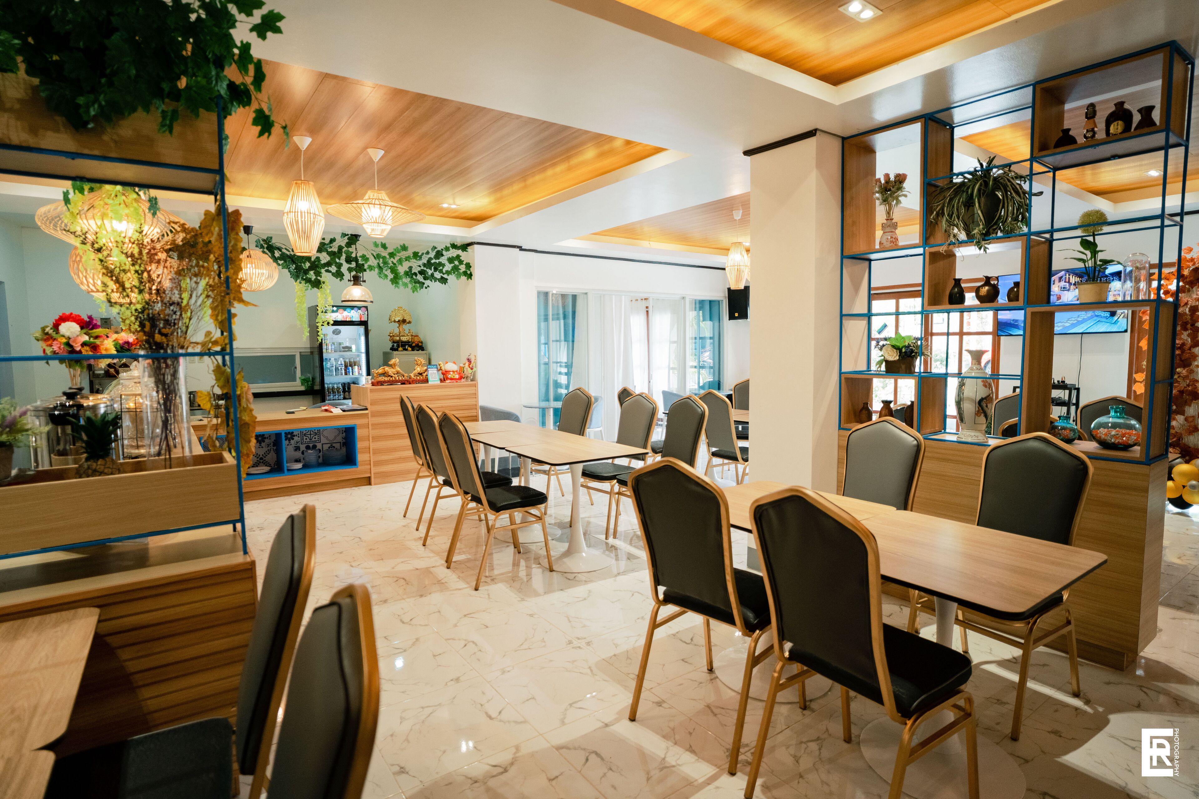 Un comedor moderno con mesas y sillas de madera, suelo de mármol y una pared decorativa con plantas.