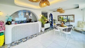 A hotel reception area with a modern design, featuring a reception desk, seating area, and decorative lighting.