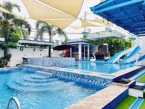 A swimming pool with multiple lanes, a children's play area, and a covered seating area. - Bernese Resort Hotel powered by Cocotel (Ligao City)