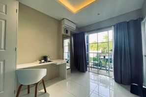 A modern room with a white desk, a chair, a window with curtains, and an air conditioning unit.