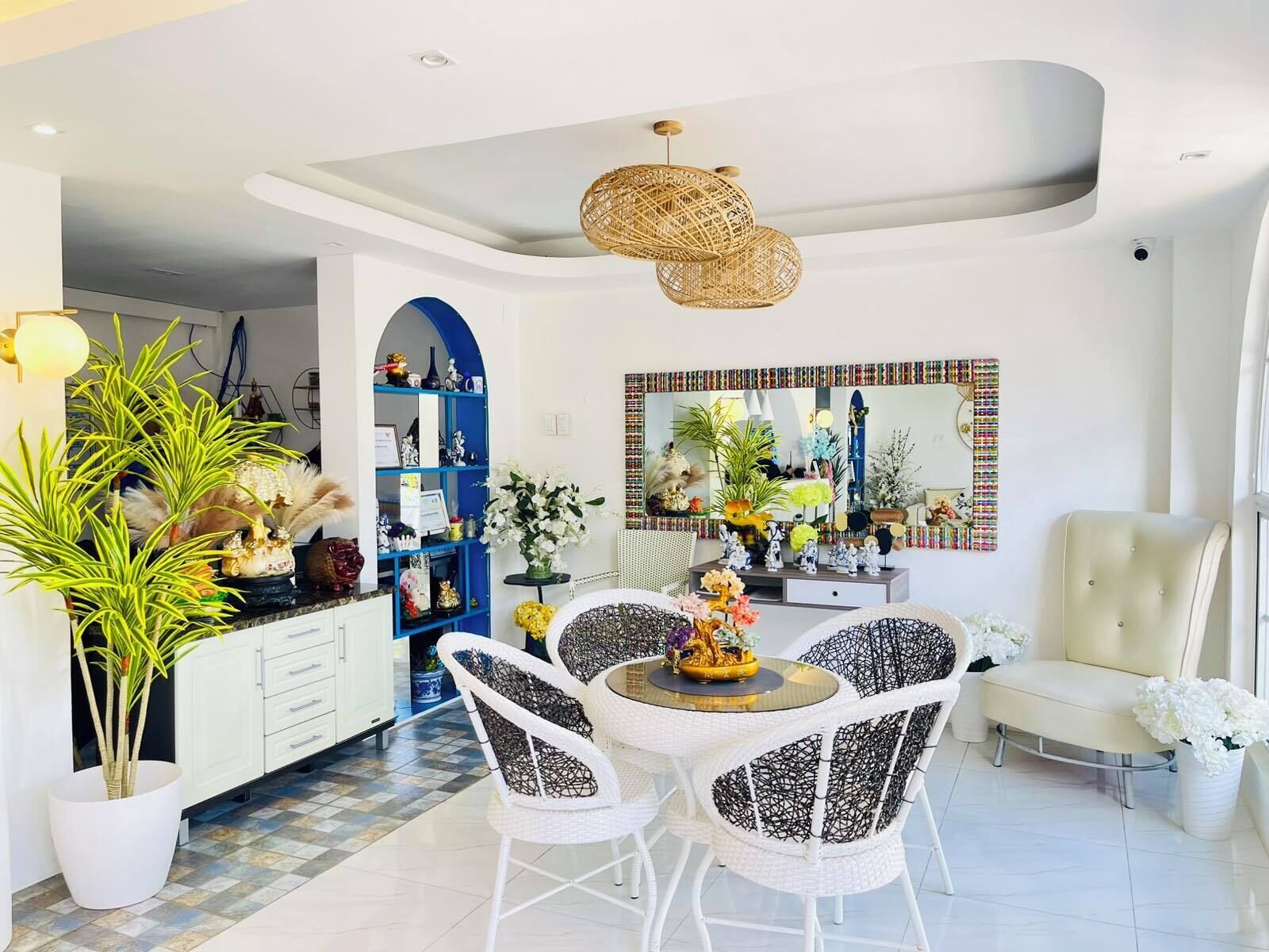 Une cuisine moderne avec des meubles blancs, un arc bleu et un coin repas comprenant des chaises blanches et une table ronde.