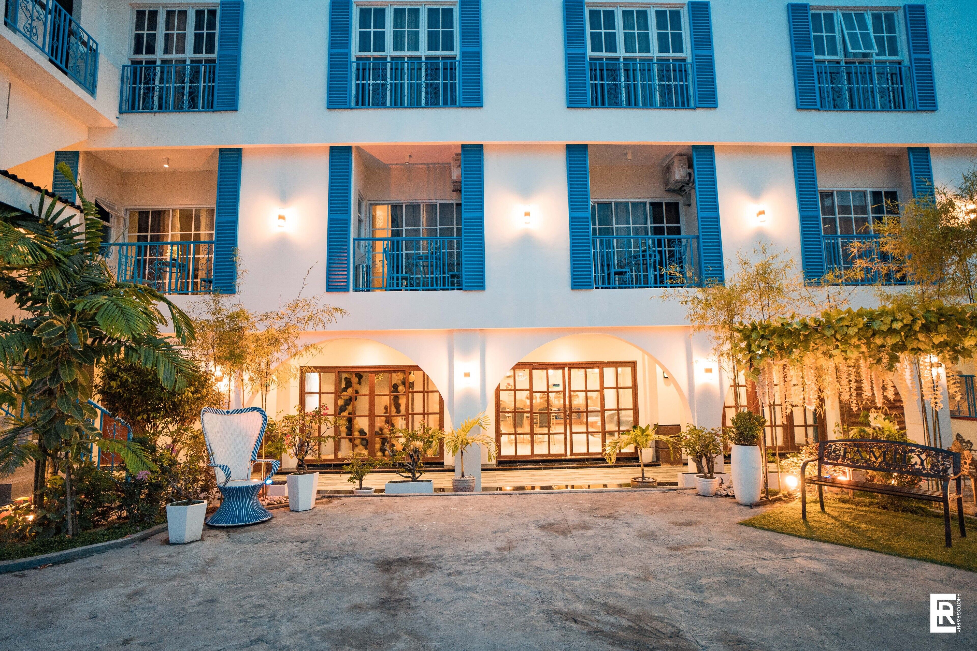 Un hotel con un patio que cuenta con un espacio de descanso, macetas con plantas y un sillón grande.