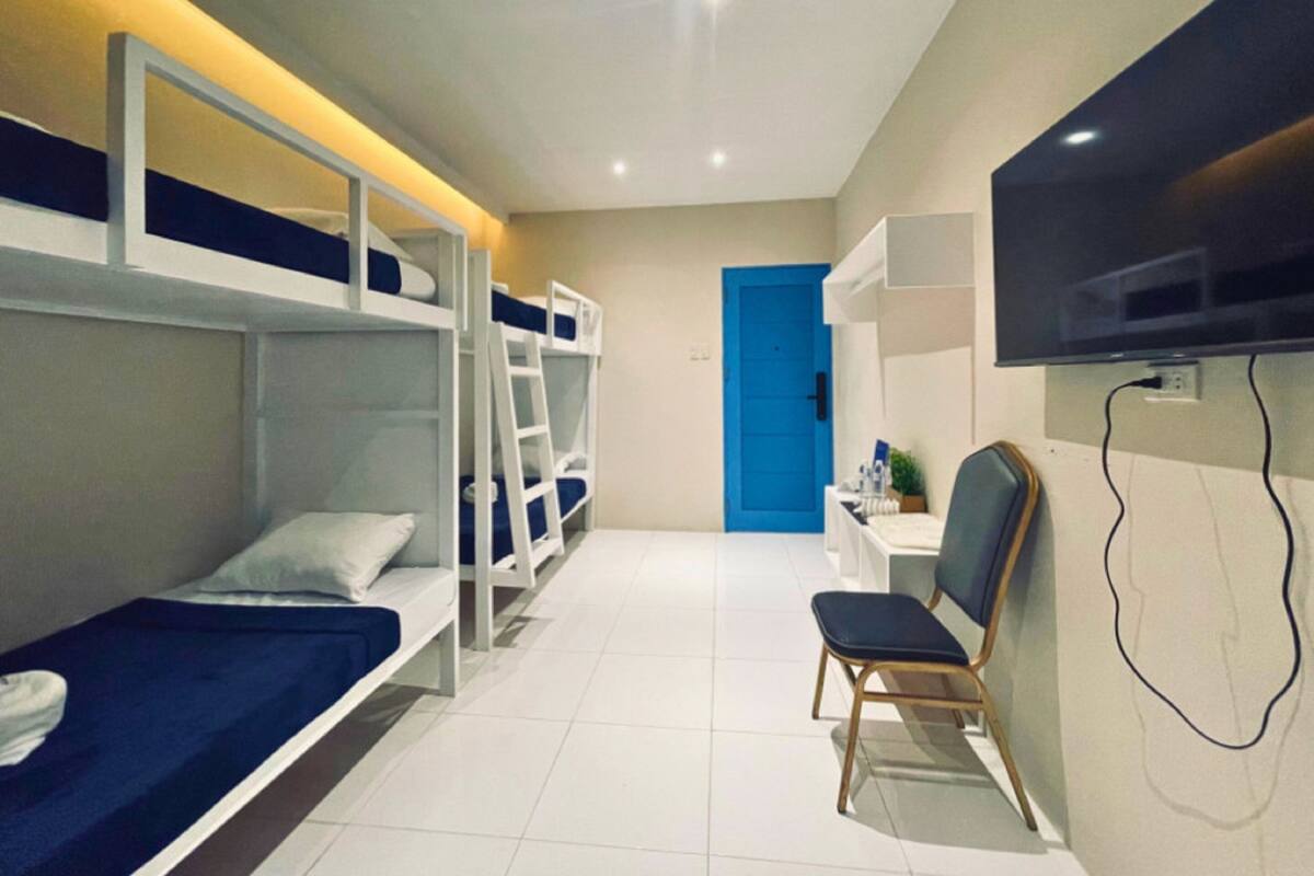 Un dormitorio con literas, un escritorio, una silla y un televisor.
