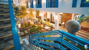 A multi-level building with blue railings and a courtyard with outdoor seating and plants.