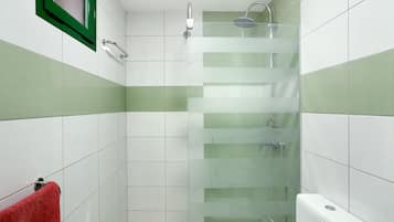 Un baño con cabina de ducha de vidrio, una toalla roja y un inodoro blanco.