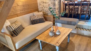 A cozy room with a wooden sofa, a wooden coffee table with decorative items, and a stone wall.