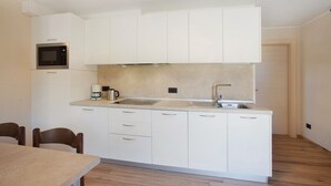 A compact kitchen with white cabinets, a microwave, a coffee maker, and a sink. - Apartment 'Al Baitin Trepalle' with Mountain View (Livigno)