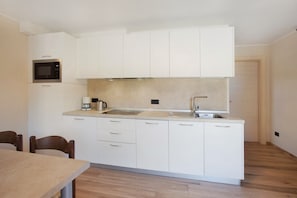 A compact kitchen with white cabinets, a microwave, a coffee maker, and a sink.