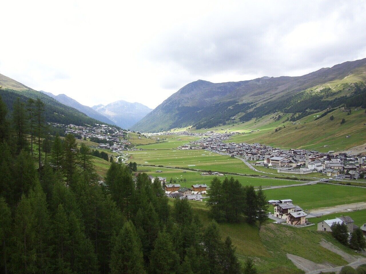 Ein Dorf in den Bergen, mit Häusern und Gebäuden, die sich über ein Tal verteilen.