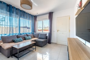 A modern living room with a sofa, a coffee table, and a TV. - Holiday Home 'Las Calas B Y D' with Shared Pool, Private Terrace and Wi-Fi (Torrevieja)