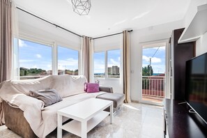 Un salon moderne avec un canapé, une table basse et un téléviseur.