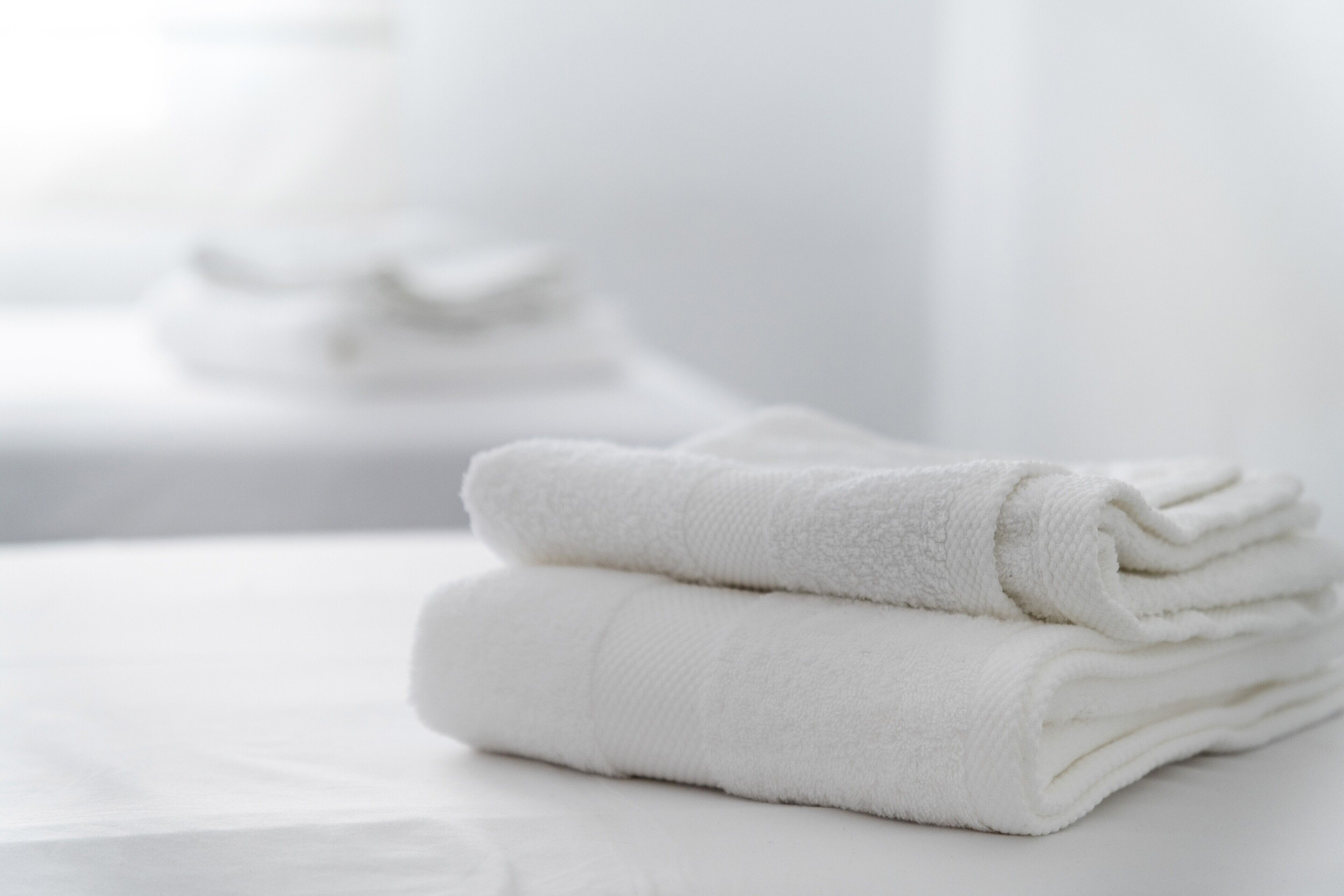 A stack of white towels on a white surface.