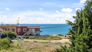 A coastal view with a building, a van, and a beach.