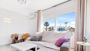 A modern living room with a sofa, a coffee table, and a dining area with chairs and a table.