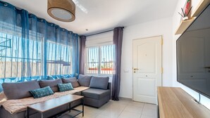 A modern living room with a sofa, a coffee table, and a TV. - Apartment 'Las Calas Deluxe B' with Shared Pool, Private Terrace and Wi-Fi (Torrevieja)