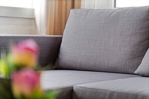 A grey sofa in a room with a window and curtains. - Apartment 'Las Calas con Terraza C' with Shared Pool, Private Terrace and Wi-Fi (Torrevieja)