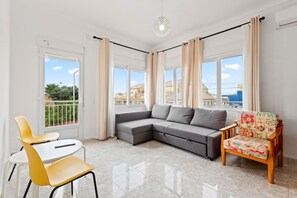 A living room with a sofa, a chair, a table, and a view of the outside. - Apartment 'Las Calas con Terraza C' with Shared Pool, Private Terrace and Wi-Fi (Torrevieja)